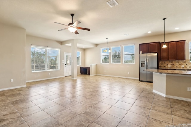 interior space featuring stainless steel refrigerator with ice dispenser, a healthy amount of sunlight, tasteful backsplash, and pendant lighting