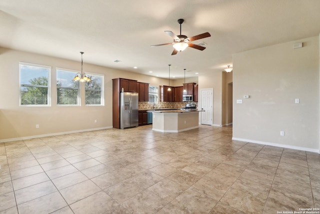 kitchen with ceiling fan with notable chandelier, a kitchen island, backsplash, stainless steel appliances, and decorative light fixtures