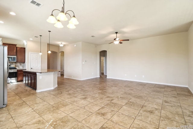 kitchen featuring light stone countertops, ceiling fan with notable chandelier, a kitchen island, hanging light fixtures, and stainless steel appliances