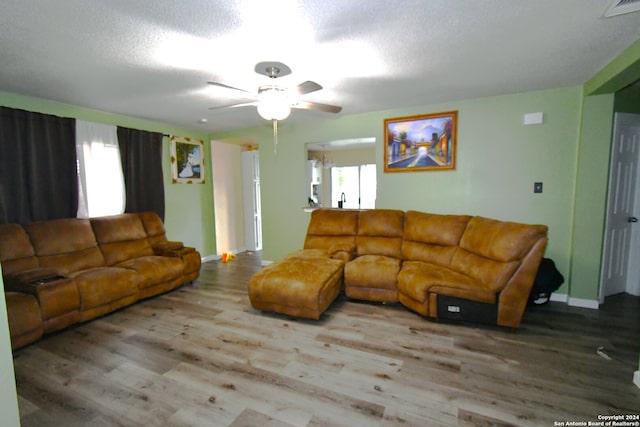 living room with a textured ceiling, light hardwood / wood-style floors, and ceiling fan