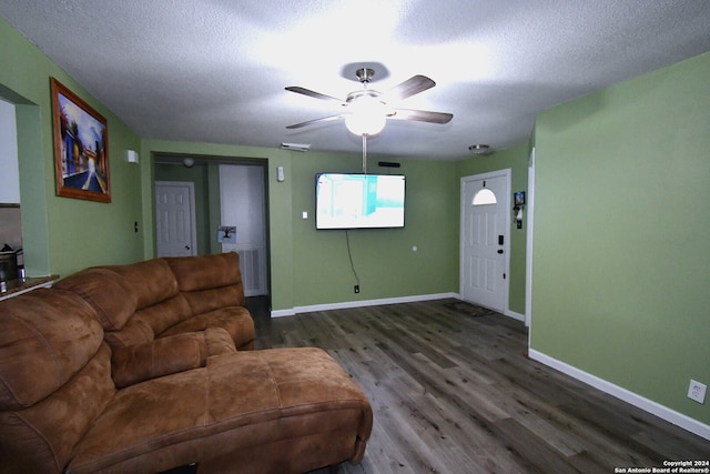 living room featuring dark wood-type flooring, a textured ceiling, and ceiling fan