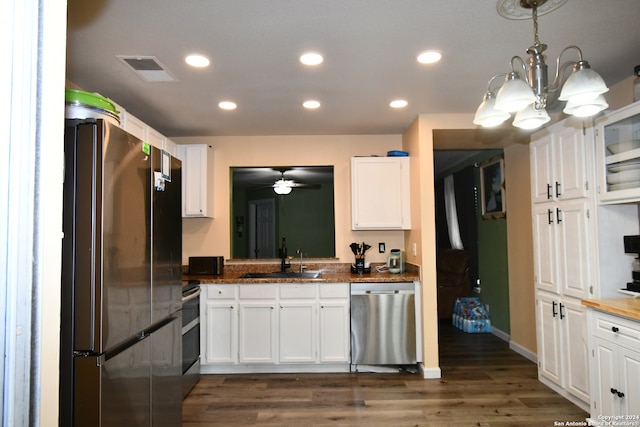 kitchen featuring sink, stainless steel appliances, decorative light fixtures, and white cabinets