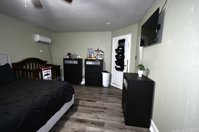 bedroom with ceiling fan, an AC wall unit, black fridge, and dark hardwood / wood-style floors