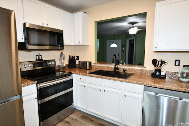 kitchen with ceiling fan, appliances with stainless steel finishes, white cabinetry, light hardwood / wood-style flooring, and sink