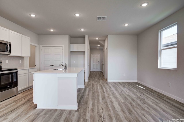 kitchen featuring appliances with stainless steel finishes, a center island with sink, white cabinetry, and sink