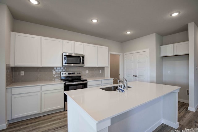 kitchen featuring white cabinetry, sink, dark wood-type flooring, stainless steel appliances, and an island with sink