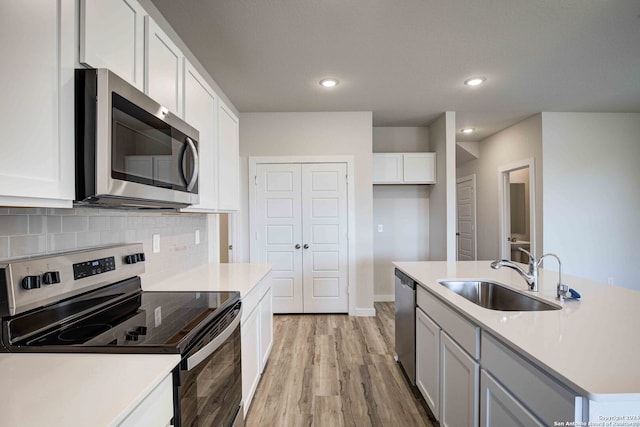 kitchen with light hardwood / wood-style flooring, stainless steel appliances, white cabinetry, and sink