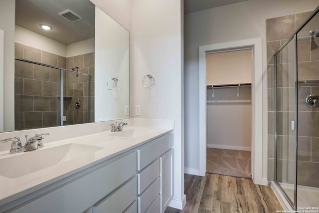 bathroom with wood-type flooring, vanity, and a shower with door