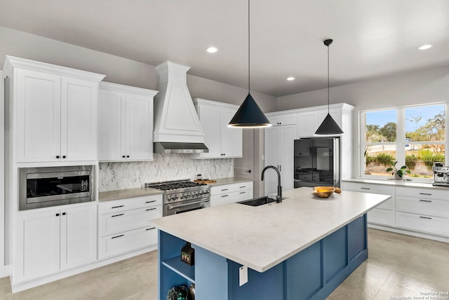 kitchen featuring appliances with stainless steel finishes, sink, hanging light fixtures, custom exhaust hood, and a center island with sink