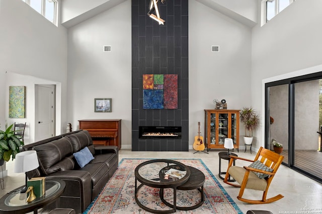 living room featuring a tiled fireplace and high vaulted ceiling