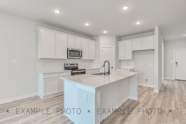 kitchen featuring an island with sink, stainless steel appliances, backsplash, sink, and white cabinetry