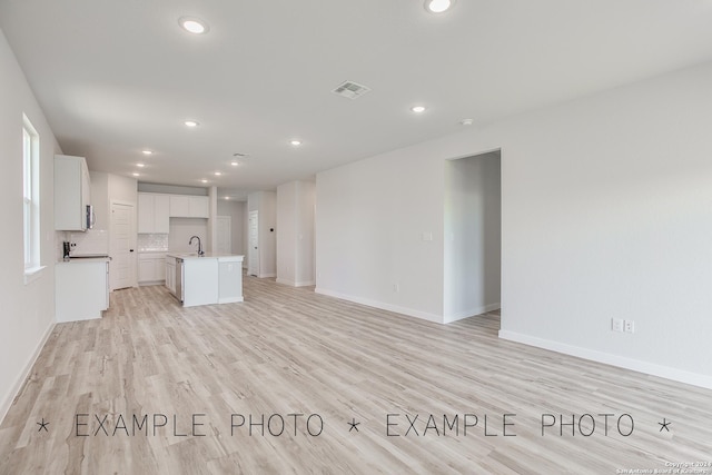 unfurnished living room with sink and light wood-type flooring