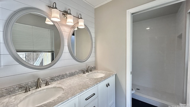 bathroom with toilet, wood walls, ornamental molding, tiled shower, and vanity