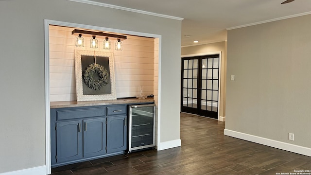 bar with ornamental molding, dark wood-type flooring, blue cabinets, and beverage cooler