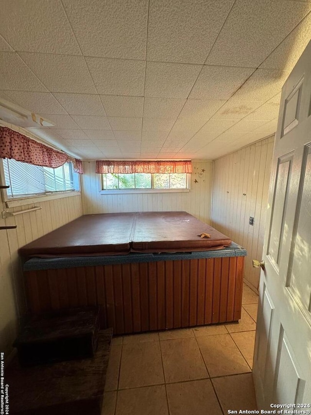 miscellaneous room with a hot tub, wooden walls, and tile patterned flooring