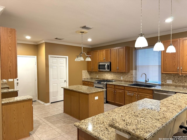 kitchen featuring appliances with stainless steel finishes, decorative light fixtures, sink, and a kitchen island