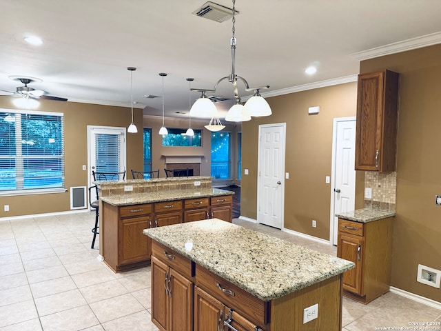 kitchen with light stone counters, crown molding, pendant lighting, a breakfast bar, and a center island