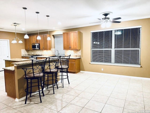 kitchen with a kitchen bar, stainless steel appliances, light stone counters, ornamental molding, and decorative light fixtures