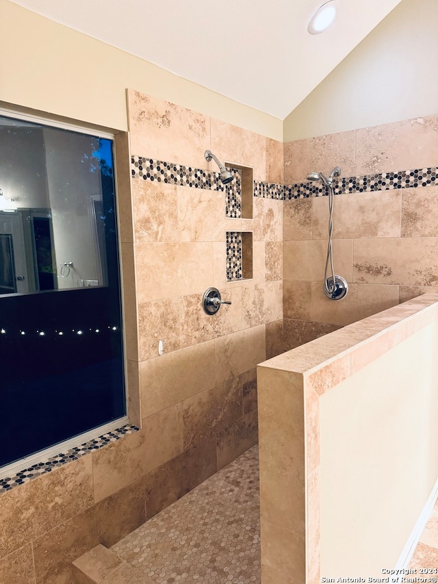 bathroom with tiled shower and lofted ceiling