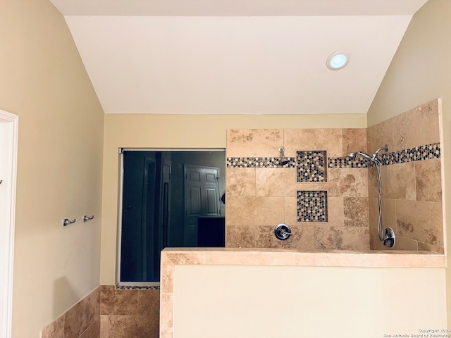 bathroom featuring vaulted ceiling and a tile shower