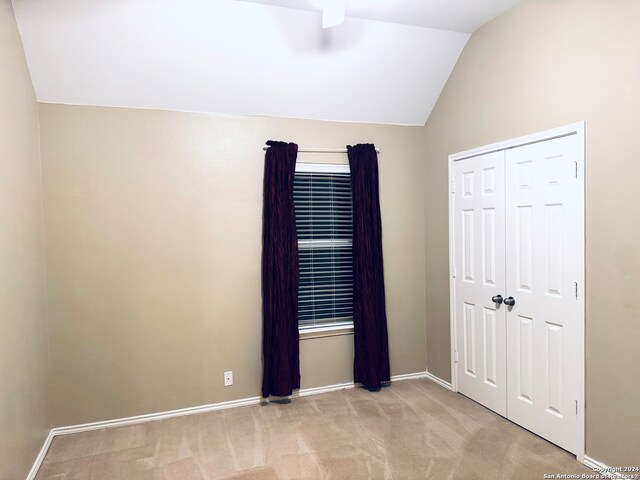 unfurnished bedroom featuring a closet, lofted ceiling, and light colored carpet