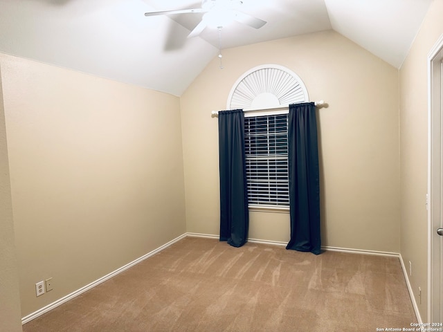 carpeted spare room featuring ceiling fan and vaulted ceiling