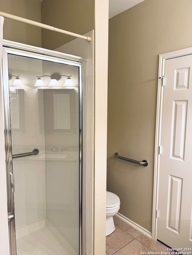 bathroom with a shower with shower door, tile patterned floors, and toilet