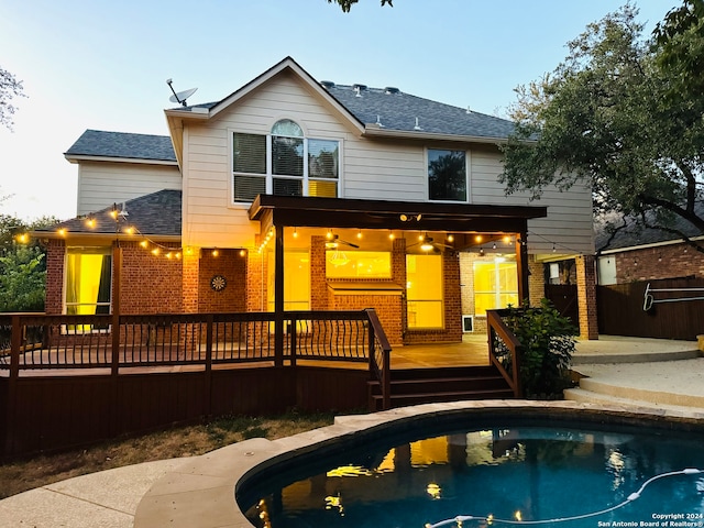 back house at dusk with a pool side deck