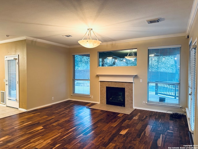 unfurnished living room with hardwood / wood-style flooring, a tiled fireplace, plenty of natural light, and ornamental molding