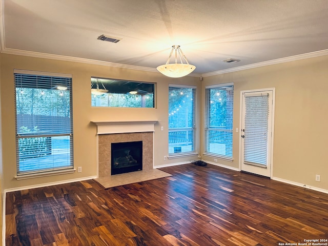 unfurnished living room featuring ornamental molding, a wealth of natural light, a tile fireplace, and dark hardwood / wood-style floors