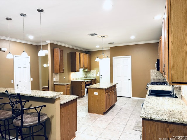 kitchen featuring sink, light stone countertops, decorative light fixtures, crown molding, and a center island