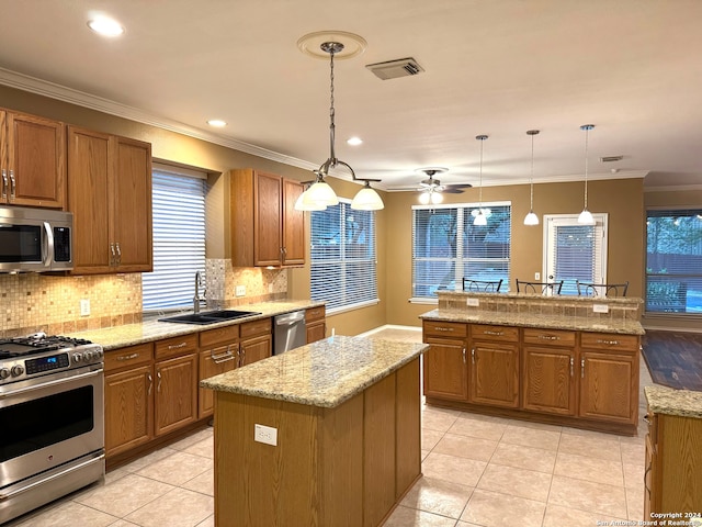 kitchen with stainless steel appliances, sink, light tile patterned floors, hanging light fixtures, and a kitchen island