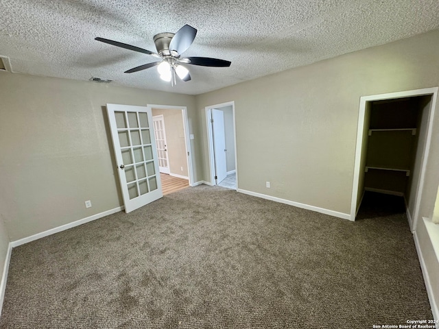 unfurnished bedroom featuring a walk in closet, carpet floors, a textured ceiling, and ceiling fan