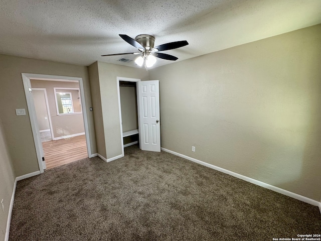 unfurnished bedroom featuring a closet, a textured ceiling, carpet flooring, and ceiling fan