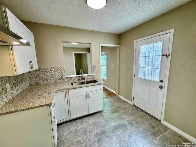 kitchen featuring range hood, sink, white cabinets, and a healthy amount of sunlight