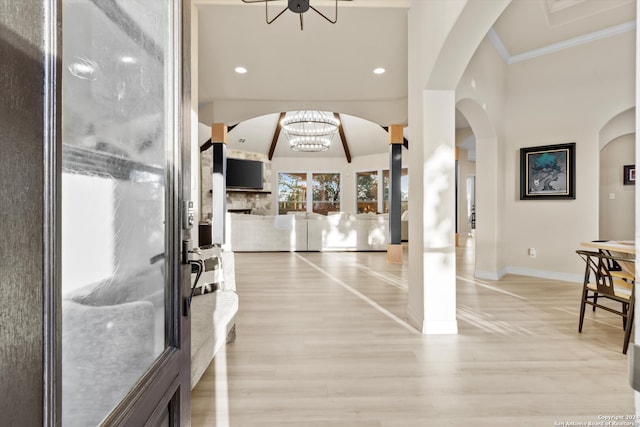 foyer featuring light hardwood / wood-style floors, a notable chandelier, ornamental molding, and a fireplace