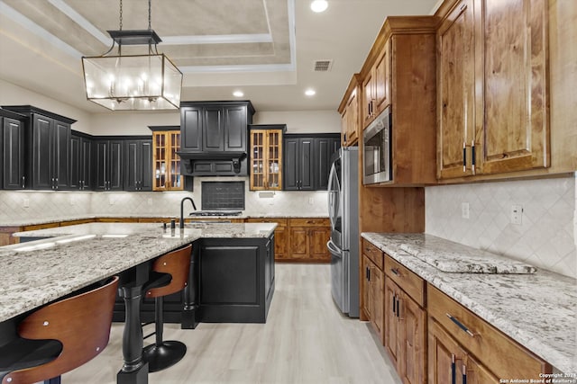 kitchen featuring a breakfast bar area, light stone countertops, stainless steel appliances, and backsplash