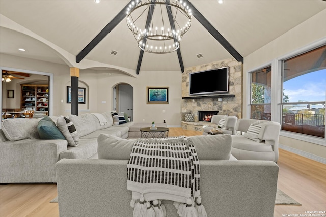 living room with a stone fireplace, light hardwood / wood-style flooring, ceiling fan, and vaulted ceiling