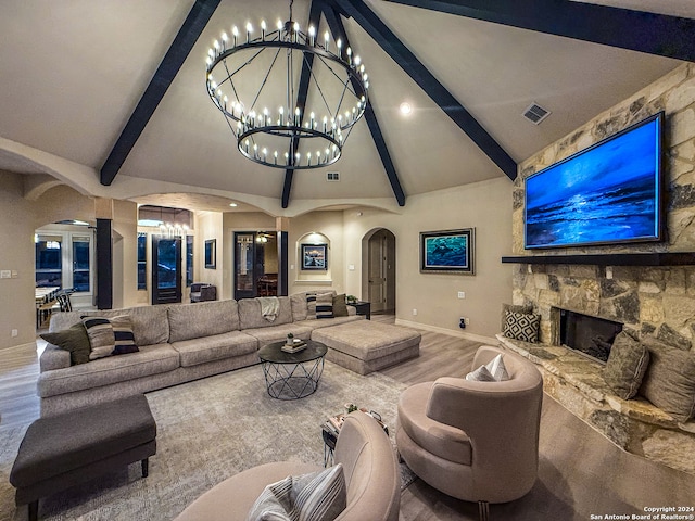 living room with lofted ceiling with beams, wood-type flooring, and a stone fireplace