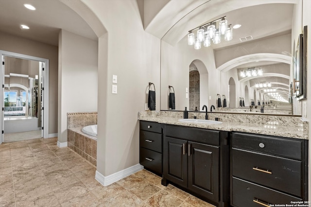 bathroom featuring vanity and tiled tub