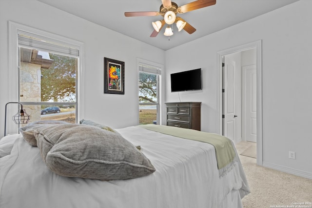 bedroom featuring light carpet, multiple windows, and ceiling fan