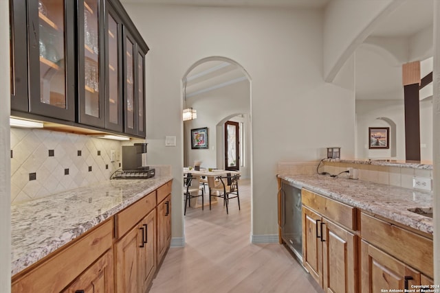 bar with light hardwood / wood-style floors, light stone countertops, ornamental molding, and backsplash