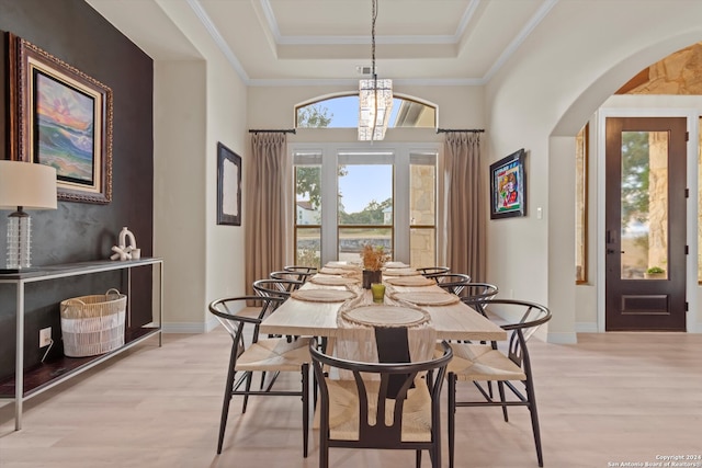 dining room with light hardwood / wood-style flooring, ornamental molding, a chandelier, and a tray ceiling