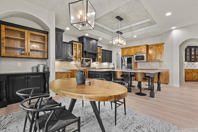 dining room with light hardwood / wood-style floors and a tray ceiling