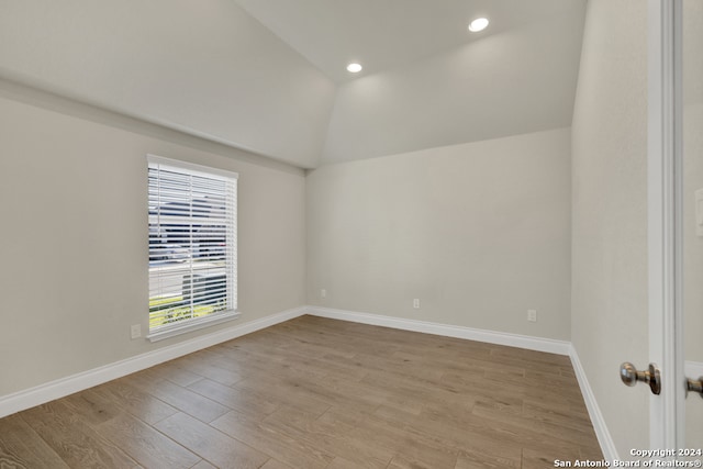 empty room with light hardwood / wood-style flooring and lofted ceiling