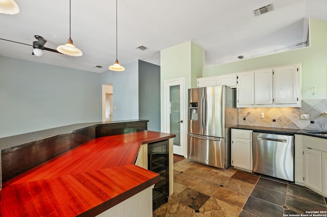 kitchen with stainless steel appliances, decorative light fixtures, beverage cooler, white cabinets, and tasteful backsplash