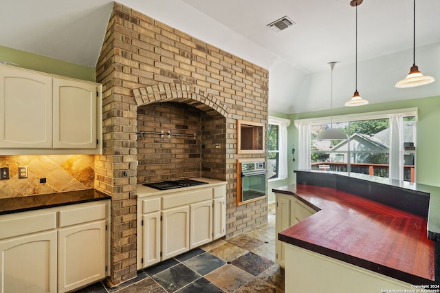 kitchen with backsplash, oven, black gas stovetop, and cream cabinets