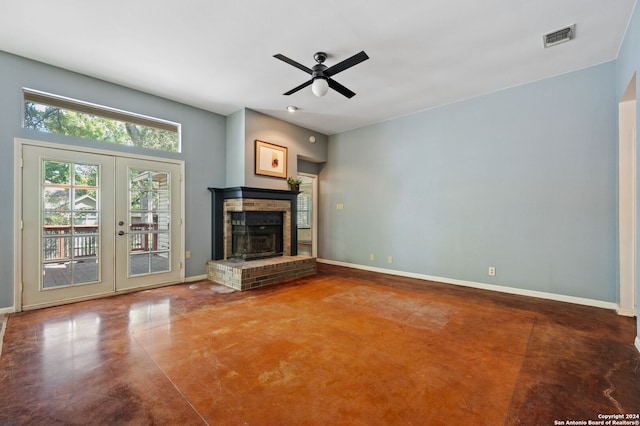 unfurnished living room with french doors, ceiling fan, a brick fireplace, and concrete flooring