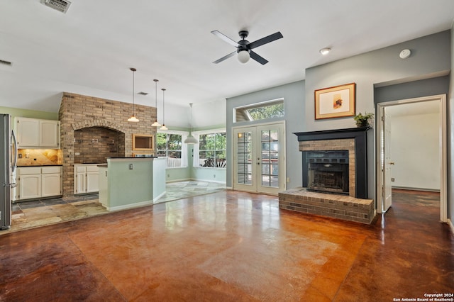 unfurnished living room with french doors, a brick fireplace, and ceiling fan