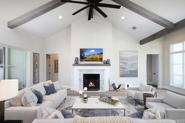 living room with a tile fireplace, ceiling fan, hardwood / wood-style floors, beam ceiling, and high vaulted ceiling